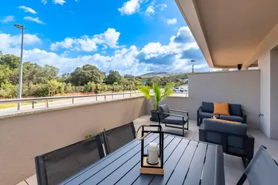 a balcony with a table and chairs on a roof at Les Vagues d'Agosta in Albitreccia
