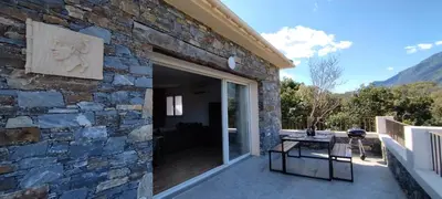 a stone house with a patio and a table on a patio at Villa Viktoriia in San-Nicolao