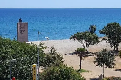 a beach with a clock tower and the ocean at Villa Viktoriia in San-Nicolao