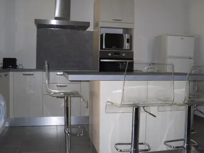 a kitchen with two bar stools and a microwave at jolie location in Porto-Vecchio