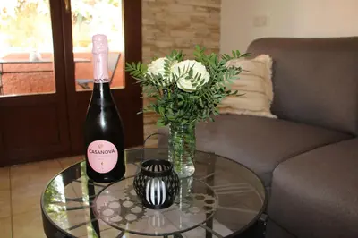 a bottle of wine and a vase with flowers on a table at Terra Corsa Duplex T2 in Porto Ota