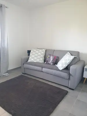 a gray couch with pillows on it in a living room at T3 Corté vue sur la Citadelle in Corte