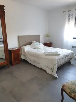 a bedroom with a bed and a chair and a mirror at T3 Corté vue sur la Citadelle in Corte