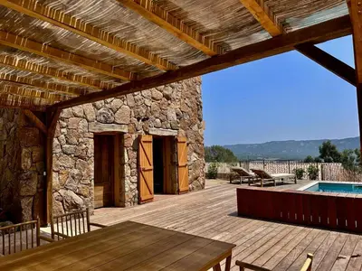 a patio with a wooden deck and a swimming pool at Bergerie de charme, piscine chauffée, vue nature entre mer et montagne, Sotta in Sotta