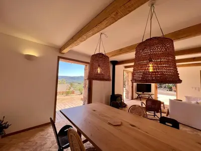 a dining room with a wooden table and two chandeliers at Bergerie de charme, piscine chauffée, vue nature entre mer et montagne, Sotta in Sotta