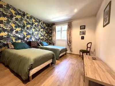 a bedroom with two beds and a table and a window at FURIANI Appartement avec Piscine dans Villa in Furiani