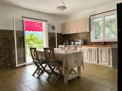 a kitchen with a table and chairs and a kitchen with a window at FURIANI Appartement avec Piscine dans Villa in Furiani