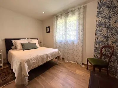 a bedroom with a bed and a window and a chair at FURIANI Appartement avec Piscine dans Villa in Furiani