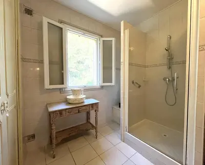 a bathroom with a shower and a table with a sink at FURIANI Appartement avec Piscine dans Villa in Furiani