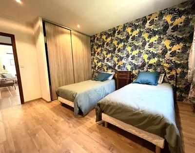 two beds in a room with floral wallpaper at FURIANI Appartement avec Piscine dans Villa in Furiani