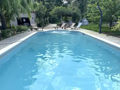 a large swimming pool with blue water in a yard at FURIANI Appartement avec Piscine dans Villa in Furiani