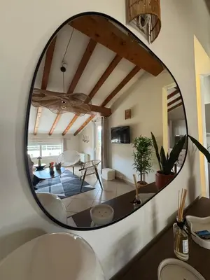 a round mirror in a living room with a table at Appartement dans résidence standing in Porto-Vecchio