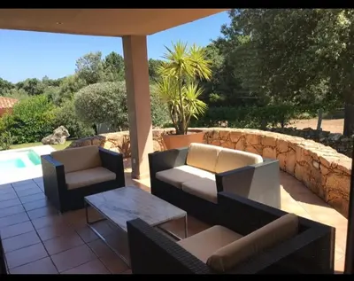 a patio with couches and a table and a pool at Villa Ysee in Porto-Vecchio