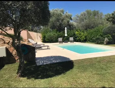 a swimming pool in a yard with two chairs and a tree at Villa Ysee in Porto-Vecchio