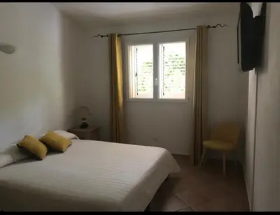a bedroom with a white bed and a window at Villa Ysee in Porto-Vecchio