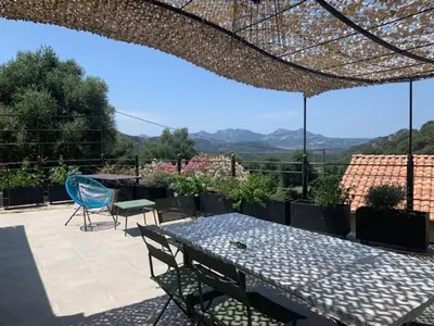 a table and chairs on a patio with a view at Belle maison en Balagne in Zilia