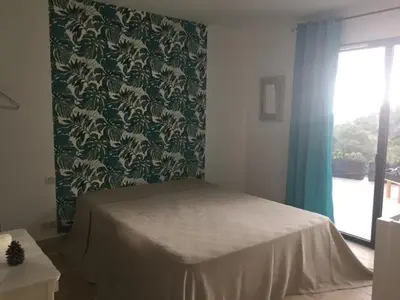 a bedroom with a bed and a green and white wall at Belle maison en Balagne in Zilia
