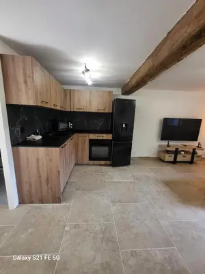 a kitchen with a black refrigerator and wooden cabinets at Maison avec spa aux portes d'Ajaccio in Carbuccia