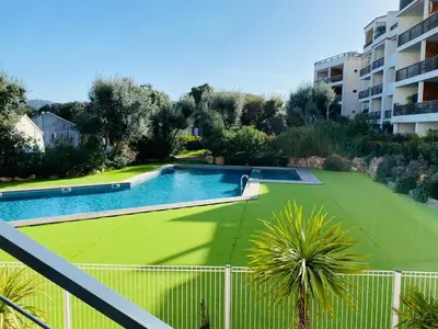a swimming pool with a green lawn in front of a building at Appartement 74 cita Di sali in Porto-Vecchio