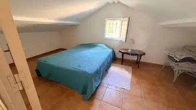 a bedroom with a bed and a table and a window at Maison de charme avec vue imprenable sur le golfe de Porto-Vecchio in Porto-Vecchio