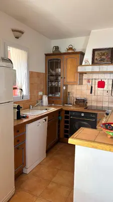 a kitchen with wooden cabinets and a white refrigerator at Maison de charme avec vue imprenable sur le golfe de Porto-Vecchio in Porto-Vecchio