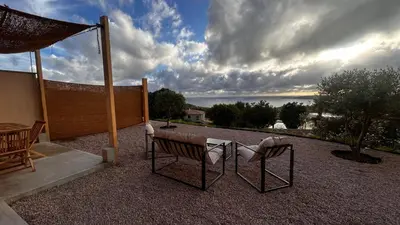 a bench sitting on a patio under a cloudy sky at Appartement vue mer Vulpaghja 01 in Cargèse
