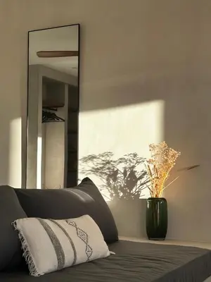 a mirror sitting next to a couch with a vase at Appartement vue mer Vulpaghja 01 in Cargèse