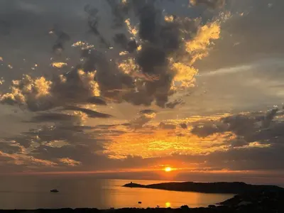 a sunset over the ocean with the sun setting at Appartement vue mer Volpaghja 02 in Cargèse