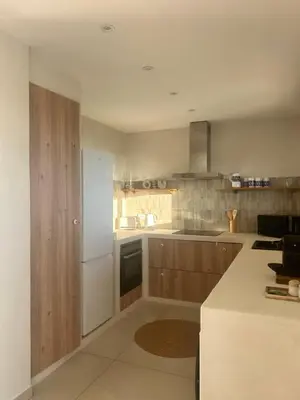 a kitchen with a white refrigerator and wooden cabinets at Appartement vue mer Volpaghja 02 in Cargèse