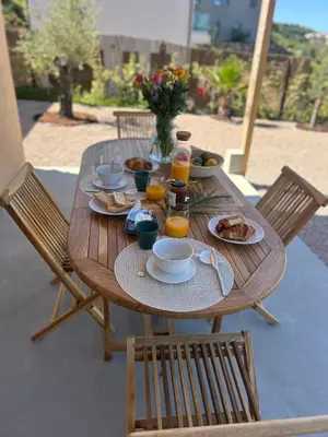 a wooden table with plates of food and orange juice at Appartement vue mer Volpaghja 02 in Cargèse