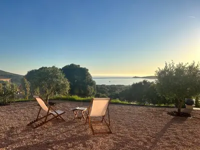 two chairs and a table sitting on top of a field at Appartement vue mer Volpaghja 02 in Cargèse