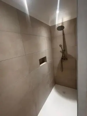 a bathroom with a shower with a large tile wall at Appartement vue mer Volpaghja 02 in Cargèse