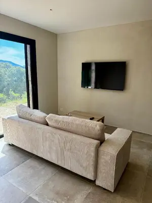 a living room with a couch and a flat screen tv at Rez-de-villa 65m2 in Propriano