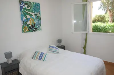 a bedroom with a white bed and a window at Villa Morticcione in Zonza