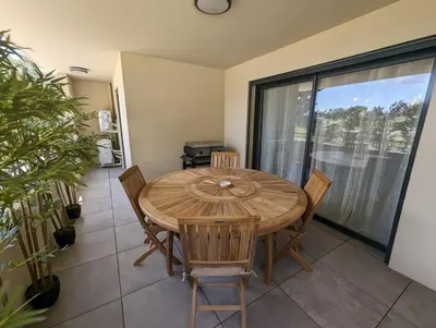 a dining room with a wooden table and chairs at Appartement neuf près du port de Porto Vecchio in Porto-Vecchio