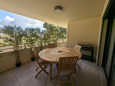 a dining room with a table and chairs on a balcony at Appartement neuf près du port de Porto Vecchio in Porto-Vecchio