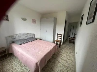 a bedroom with a pink bed and two chairs at Appartement avec balcon à Marignana, 30 m², 4 pers. in Marignana