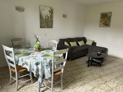 a living room with a table and a couch at Appartement convivial à Marignana, proche de la nature in Marignana