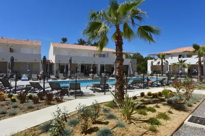 a resort with a pool and chairs and a palm tree at T3 bord de mer en Corse N130 in Linguizzetta