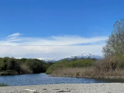 a river with snow capped mountains in the background at T3 bord de mer en Corse N130 in Linguizzetta