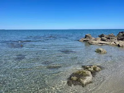 a beach with some rocks in the water at Appartement T2 bord de mer N165 in Linguizzetta