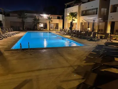 a swimming pool with chairs and a building at night at Appartement T2 bord de mer N165 in Linguizzetta