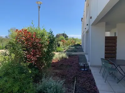 a garden next to a building with a table and chairs at Appartement T2 bord de mer N165 in Linguizzetta