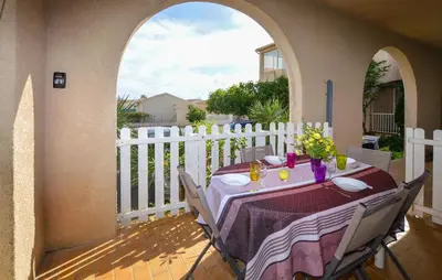 a table on a balcony with a white fence at Appartement Residence Piscine in Prunete