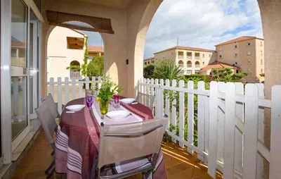 a table on a balcony with a white fence at Appartement Residence Piscine in Prunete