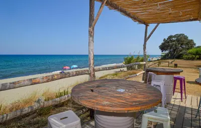 a wooden table and chairs next to the beach at Appartement Residence Piscine in Prunete