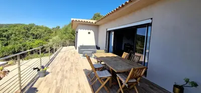 a deck with a wooden table and chairs on a house at Villa moderne avec piscine 4 étoiles in Sotta