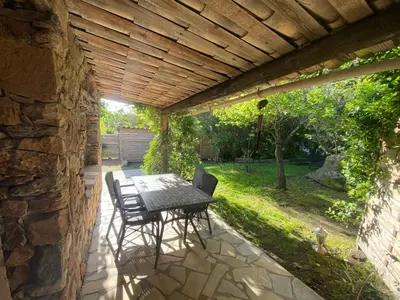 a patio with a table and chairs under a wooden ceiling at Résidence Anitrella in Porto-Vecchio