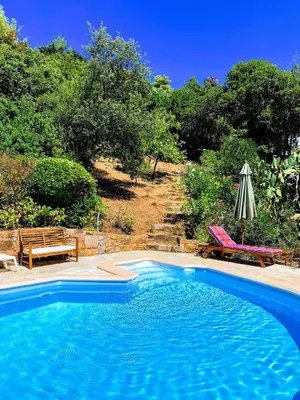 a swimming pool with two chairs and an umbrella at Superb sea view villa with pool and big garden in Pietrosella