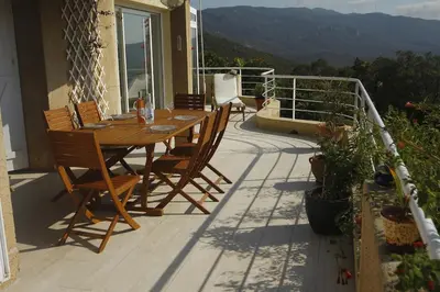 a wooden table and chairs on the balcony of a house at Superb sea view villa with pool and big garden in Pietrosella